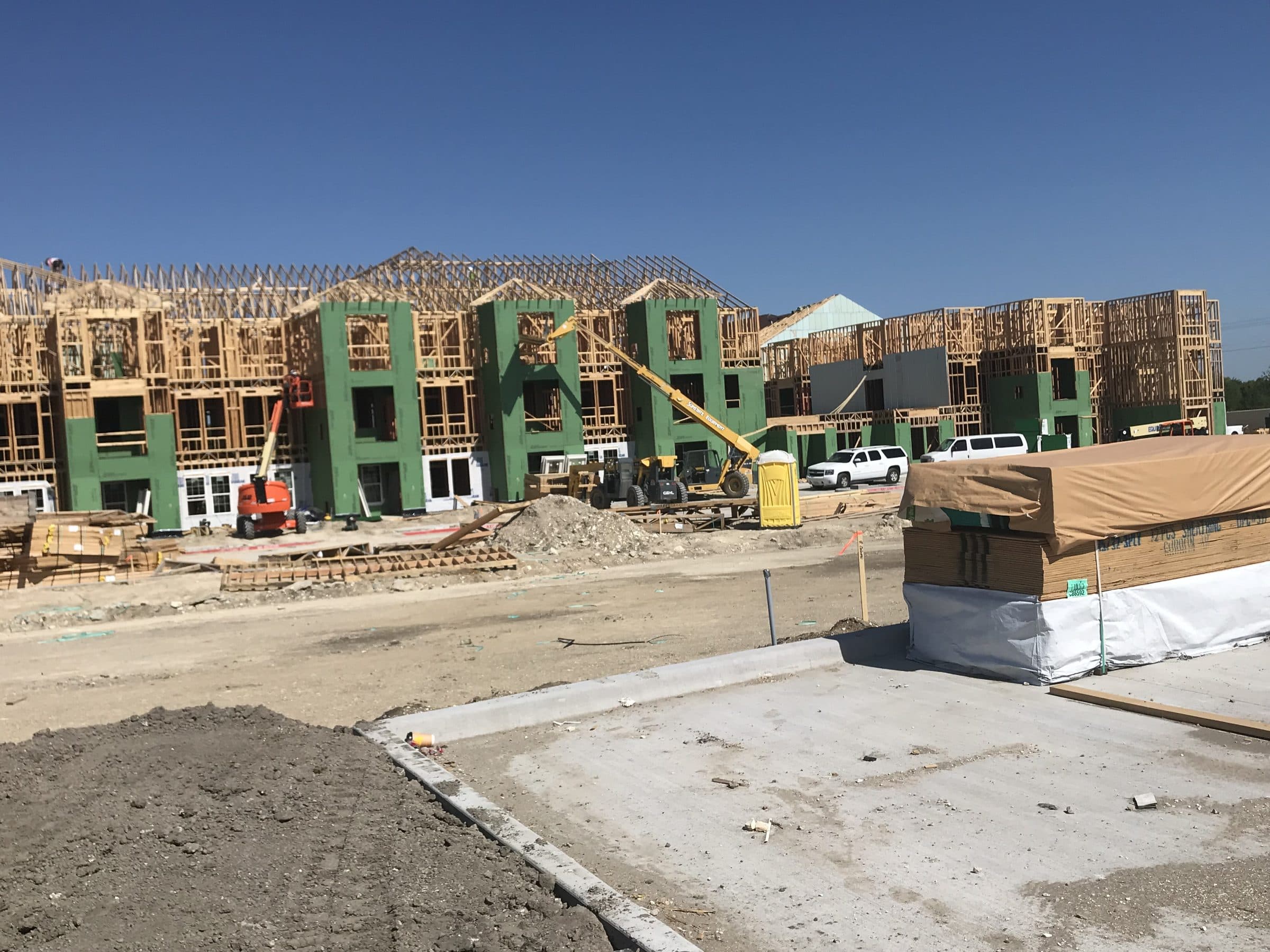 Framing and sheathing across the site, boom lift and telehandler working