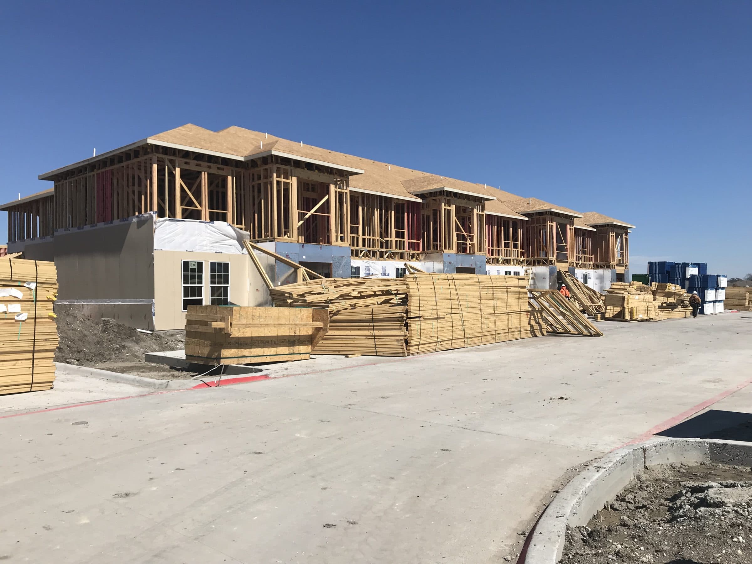 Wood framing with lumber packs staged on the drive