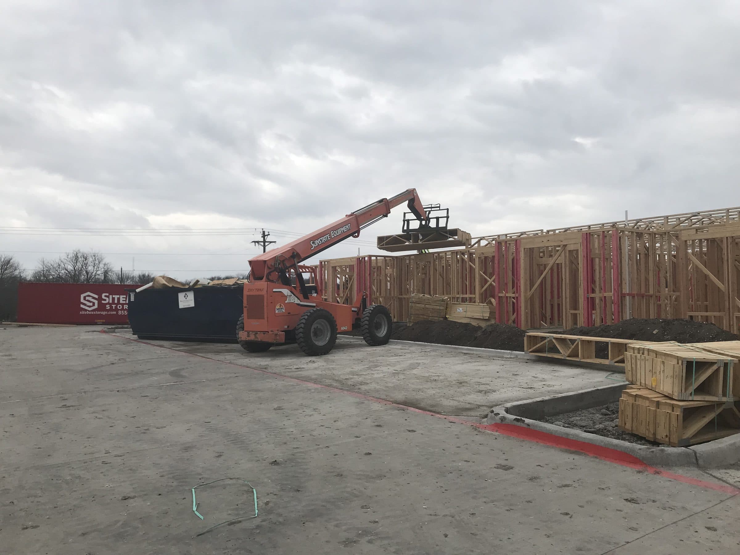 A telehandler lifting roof trusses into place