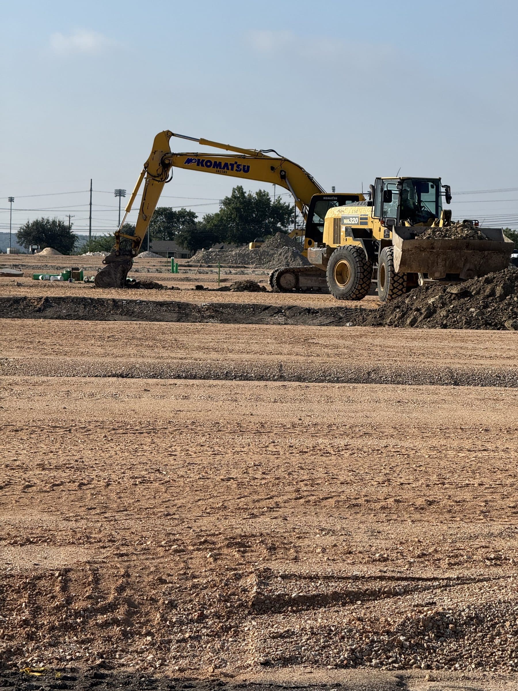 A wheel loader and excavator working the lime-treated subgrade