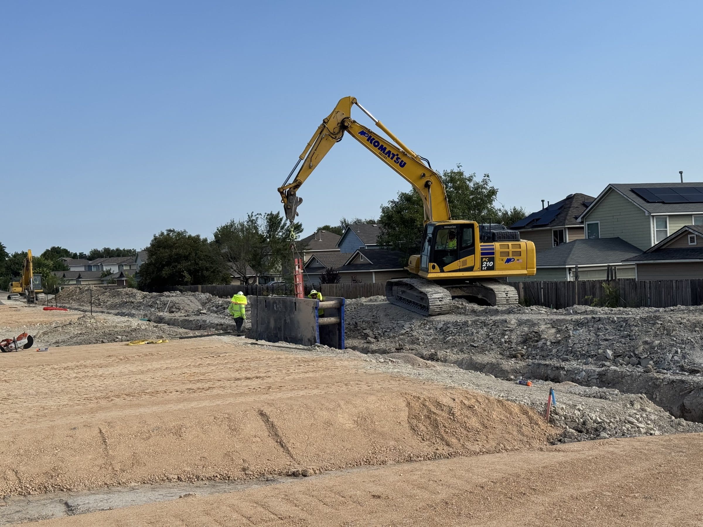 An excavator setting a trench box for the wet utilities