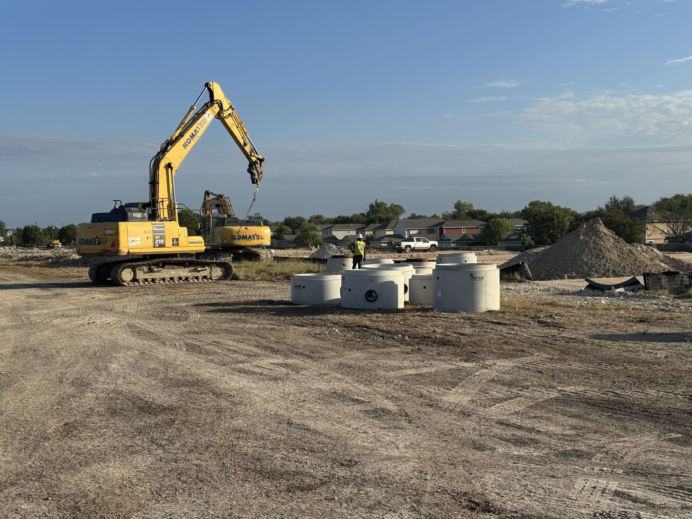 Precast manhole barrels staged on the graded pad