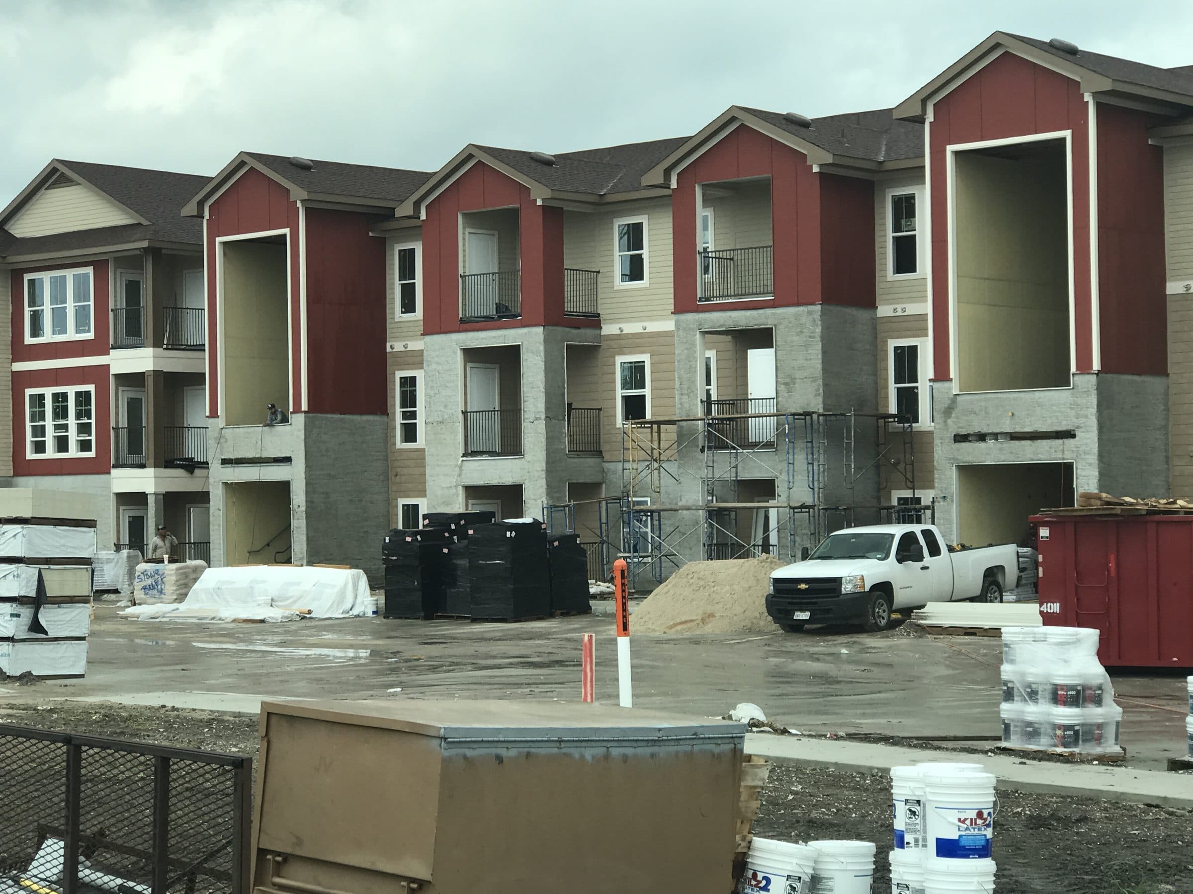 Three-story elevations going up, siding and stone underway on a wet lot